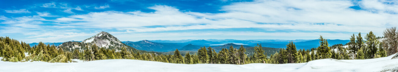 Mountains, lakes, and a forest with snow - photographed as a wide panorama at Lassen Volcanic...