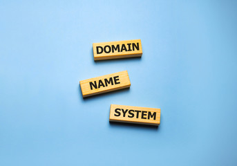 DNS - Domain Name System, acronym technology concept on wooden blocks on blue.