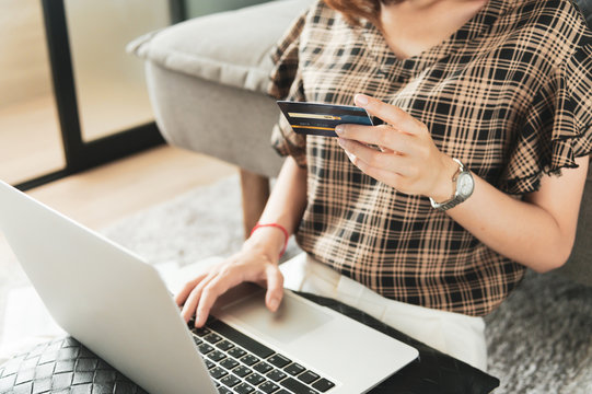Young Asian woman using credit card for shopping online at her home