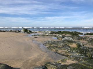 Sea waves breaking on rocks in Esposende, Portugal. Sea, beach boulders, pebble shore and waves in the morning.