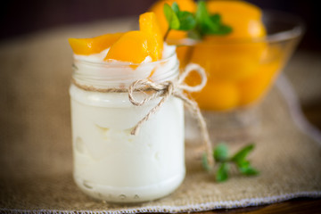 homemade sweet yogurt with slices of pickled peaches in a glass jar