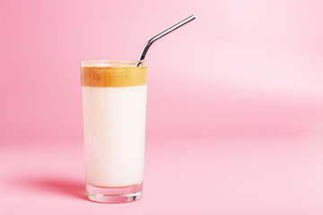  Dalgona coffee in a glass cup and with a metal eco straw on a pink background. Minimalism, copy space