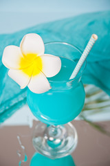 Exotic tropical Blue Curacao cocktail drink in a glass with Plumeria frangipani flower.