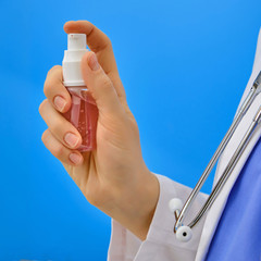 A nurse with hand sanitizer. Doctor holding a sanitator on a blue background, close-up. Concept of disinfection in a coronavirus epidemic