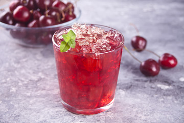 Glass with fresh homemade cherry sweet iced tea or cocktail, lemonade with mint. Refreshing cold drink. Summer party.