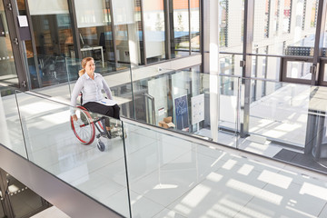 Junge Frau im Rollstuhl auf der Galerie im Unternehmen