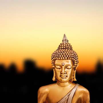 Bronze Zen Buddha Statue on golden sunset background.