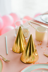 Golden birthday caps on pink party table