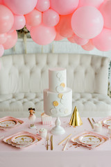 Little girl birthday party table with beautiful cake. Table setting decorated pink ballond garland