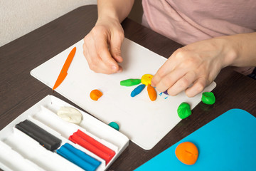 Fototapeta premium Playing with a child, modeling plasticine at home with mom, hands closeup
