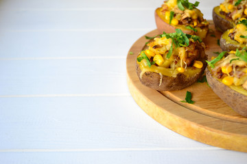 Stuffed baked potato with mushrooms, onion and corn on a white background.