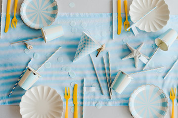 Prepared birthday table with paper elegant tableware for children party in blue and yellow colors. Baby shower day, Top view