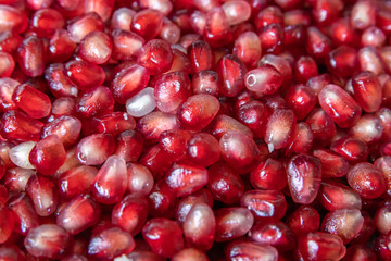 Red grains of fresh pomegranate, closeup texture, defocus on the edges
