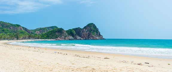 Fototapeta na wymiar Secluded tropical beach turquoise transparent water palm trees, Bai Om undeveloped bay Quy Nhon Vietnam central coast travel destination, desert white sand beach no people clear blue sky