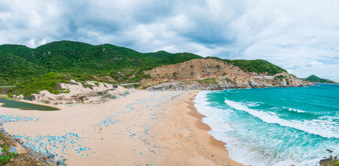 Expansive view of scenic tropical bay, gorgeous blue waving sea, plastic rubbish pollution on sand beach. Easternmost coast in Vietnam, Phu Yen province between Da Nang and Nha Trang.
