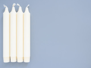 Long white candles are lined up in a row, isolated on a gray background, close-up, top view, mockup, copy space. Interior items, decorative decorations for the house. Blank for a designer or postcard