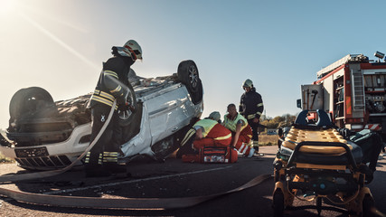 On the Car Crash Traffic Accident Scene: Team of Paramedics and Firefighters Rescue Injured People...