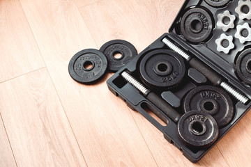 a set of dumbbells for sports at home on a wooden floor for the period of isolation. box with dumbbells
