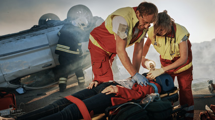 On the Car Crash Traffic Accident Scene: Paramedics Saving Life of a Female Victim who is Lying on...