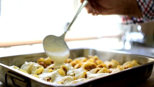 Preparation of homemade lumaconi filled in with tomato sauce and minced meat. Adding some cheese and b&eacute;chamel sauce. Italian pasta recipe