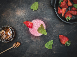 Strawberries milk shake with honey and mint leaves on vintage table. Overhead shot with copy space.