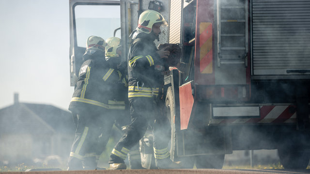 Rescue Team of Firefighters Arrive on the Car Crash Traffic Accident Scene on their Fire Engine. Firemen Grab their Tools, Equipment and, Gear from Fire Truck, Rush to Help Injured, Trapped People