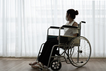Asian young handicapped woman with sad and hopeless feeling sitting on the wheelchair alone in the...