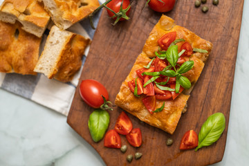 Focaccia con pomodorini pachino e basilico su tagliere di legno