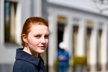 Junges Mädchen mit rötlichem Haar lächelt in die Kamera -Brustbild outdoor, seitlicher Blick