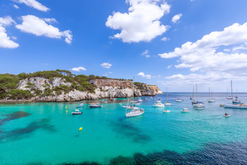 View of the most beautiful bay Cala Macarella of the island Menorca with emerald water and a lot of yachts on the sea. Balearic islands, Spain