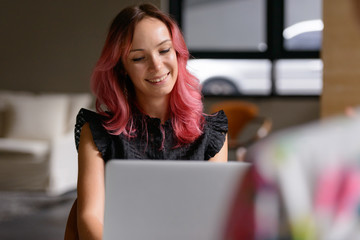 Happy businesswoman using laptop and talking with man indoors