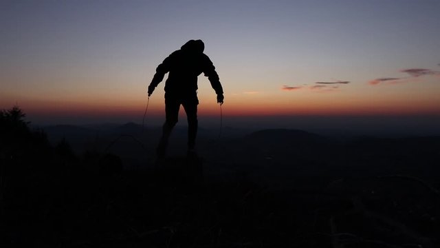 Young man trying to learn new skills during sunset on Ondrejnik mountain, Beskydy, czech republic. Athlete teaches how to jump rope. Failed attempts. Beginner. Needs a lot of training