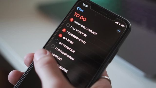 Ticking off point of a to do list on cell phone, close up, slow motion
