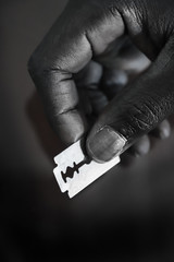 Black Hands Holding Razor Blades for Circumcision 