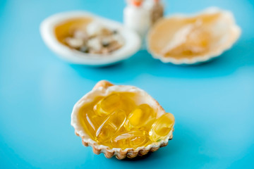 Omega 3 capsules on shell, sea salt and fish oil pills.
