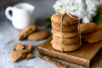 Homemade oatmeal cookies on a wooden cutting board on old table background