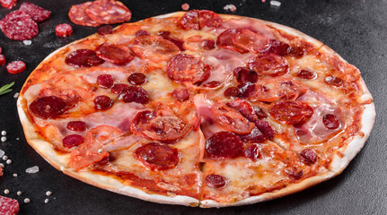 Pepperoni pizza with mozzarella cheese, salami, tomatoes, pepper and spices