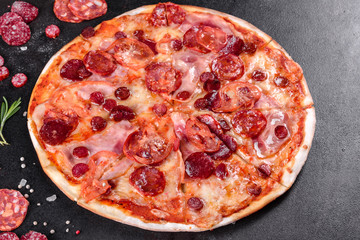 Pepperoni pizza with mozzarella cheese, salami, tomatoes, pepper and spices