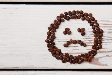 Bad coffee concept. Unhappy sad smiley made of coffee beans on white wood.