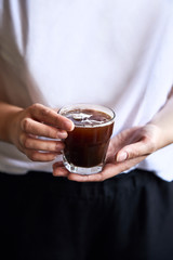 Woman holding glass with ice coffee