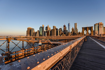 Blick über die menschenleere Brooklyn Bridge auf die Silhouette von Manhattan Downtown zum Sonnenaufgang im Sommer