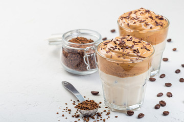Trendy korean drink Dalgona coffee with ice, garnished with grated chocolate, light gray background, horizontal, copy space