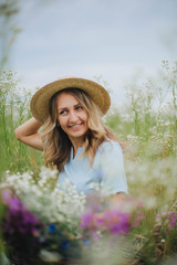 beautiful blonde girl in a field of daisies. woman in a blue dress in a field of white flowers. girl with a bouquet of daisies. summer tender photo in the village. wildflowers. girl in a straw hat