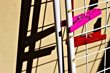 A pair of red and fuchsia clothespins attached to the clothehorse against the wall (Pesaro, Italy,...