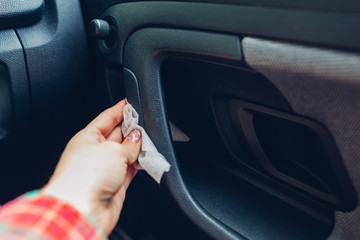 Coronavirus car disinfection. Driver cleans door handle with wet antibacterial alcoholic wipes. Covid-19 pandemic