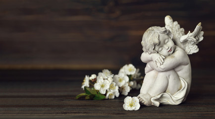 Guardian angel and white spring flowers on wooden background with copy space