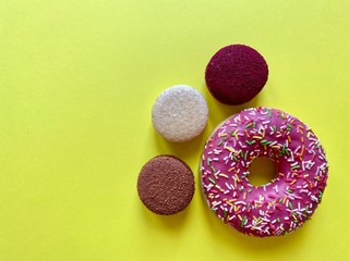 three colored macaroons and a donut on a yellow background bottom right.