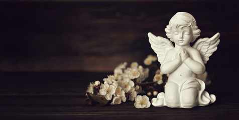 Condolence card with guardian angel and white spring flowers on wooden background with copy space