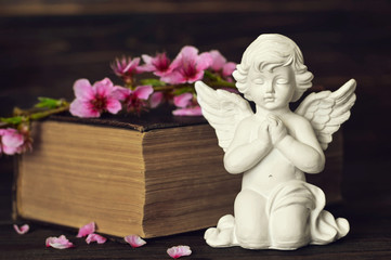 Guardian angel, spring flower branch and book on wooden background