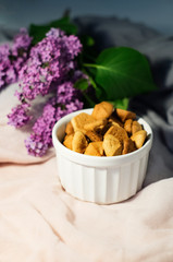 Cookies in a vase on fabric and sprigs of lilac